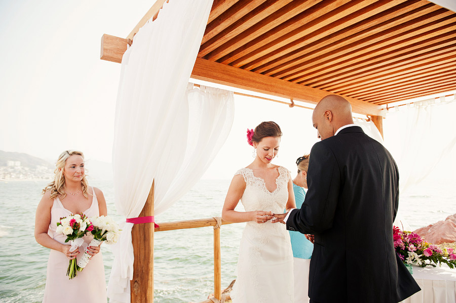 Ring exchange during the wedding of Danielle & Mick under the gazebo on the peir on the beach at the Sheraton Buganvilias Wedding Photos.